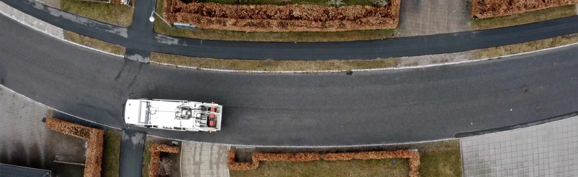 luftfoto af skraldebil der kører på villavej